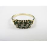 A diamond and emerald dress ring, the stones claw and crown set in a tiered diagonal arrangement