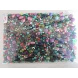 A large quantity of vintage glass and composition beads in tones of pink, green and purple