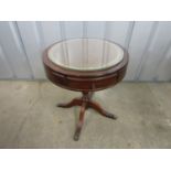 A reproduction mahogany drum table with glass top