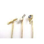 Three early 20th Century yellow metal stick pins, two set with a bar and seed pearls to the