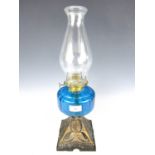 A Victorian oil lamp with blue glass reservoir and cast base