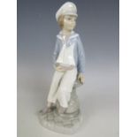 A Lladro figurine of a young boy holding a pond yacht