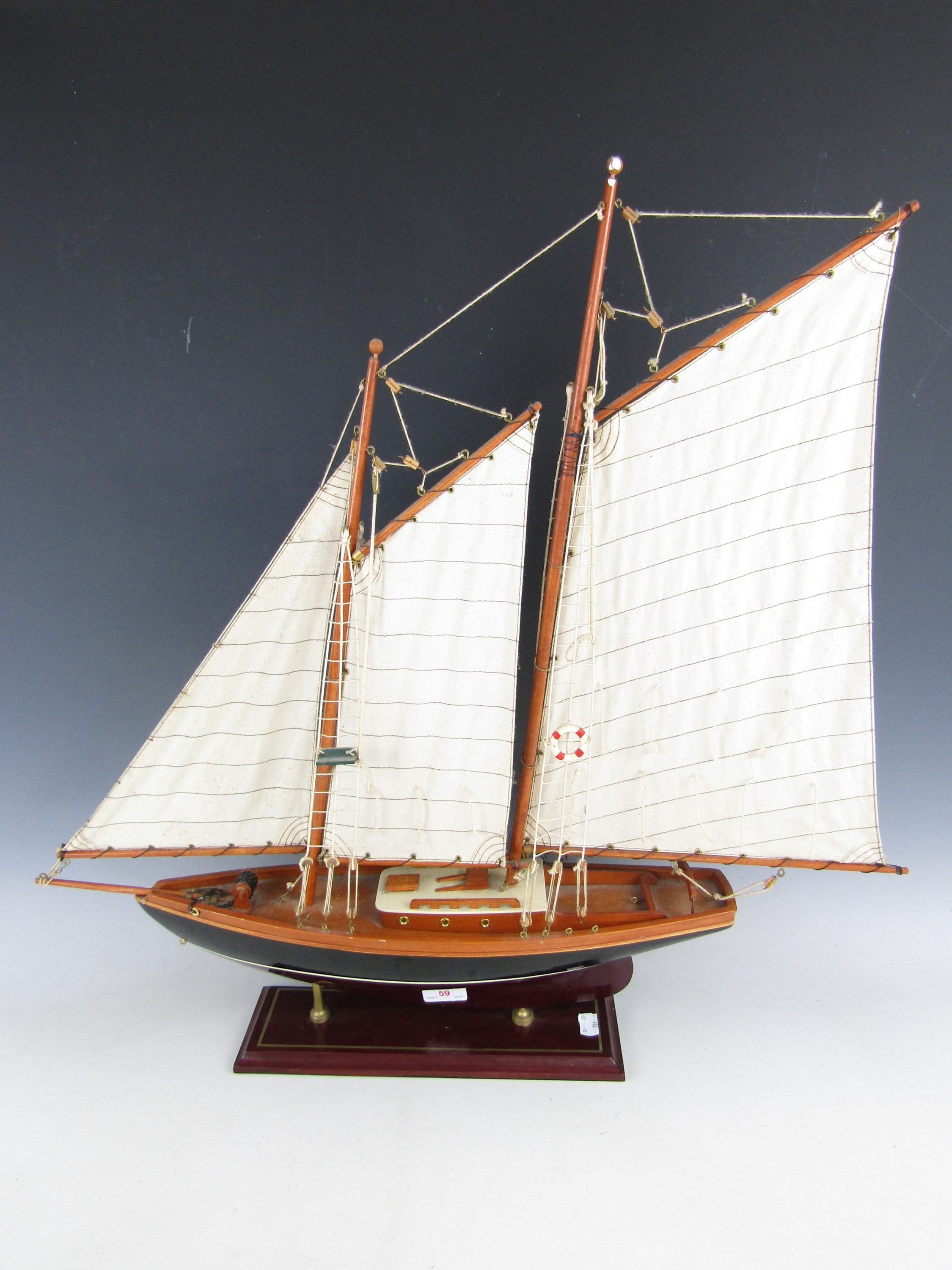 A wooden scale model of a yacht with canvas sails