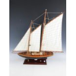 A wooden scale model of a yacht with canvas sails