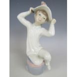 A Lladro figurine of a young girl trying on a summer bonnet