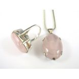 A contemporary rose quartz cabochon and white metal pendant necklace, the stone held in a