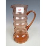 A 1930s coral-tinted blown glass lemonade jug of knopped form, 25 cm