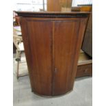 A 19th Century oak bow fronted hanging corner cupboard with mahogany cross-banding, 75 x 48 x 119