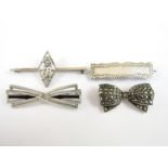 Four early 20th Century silver and white metal brooches, including one bar brooch with central