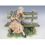 A Capo di Monte figurine modelled as a lady on a bench