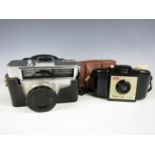 A vintage Kodak Brownie 127 compact film camera together with one other similar