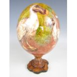 A Mauritian decoupage ostrich egg, mounted on a turned wooden socle