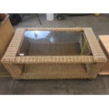 A contemporary glass topped wicker coffee table