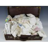 A vintage hide case containing a quantity of early 20th century hand embroidered table linens and