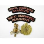 Two British Army cap badges and a pair of reproduction cloth shoulder titles