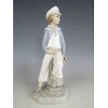 A Lladro figurine of a young boy holding a pond yacht