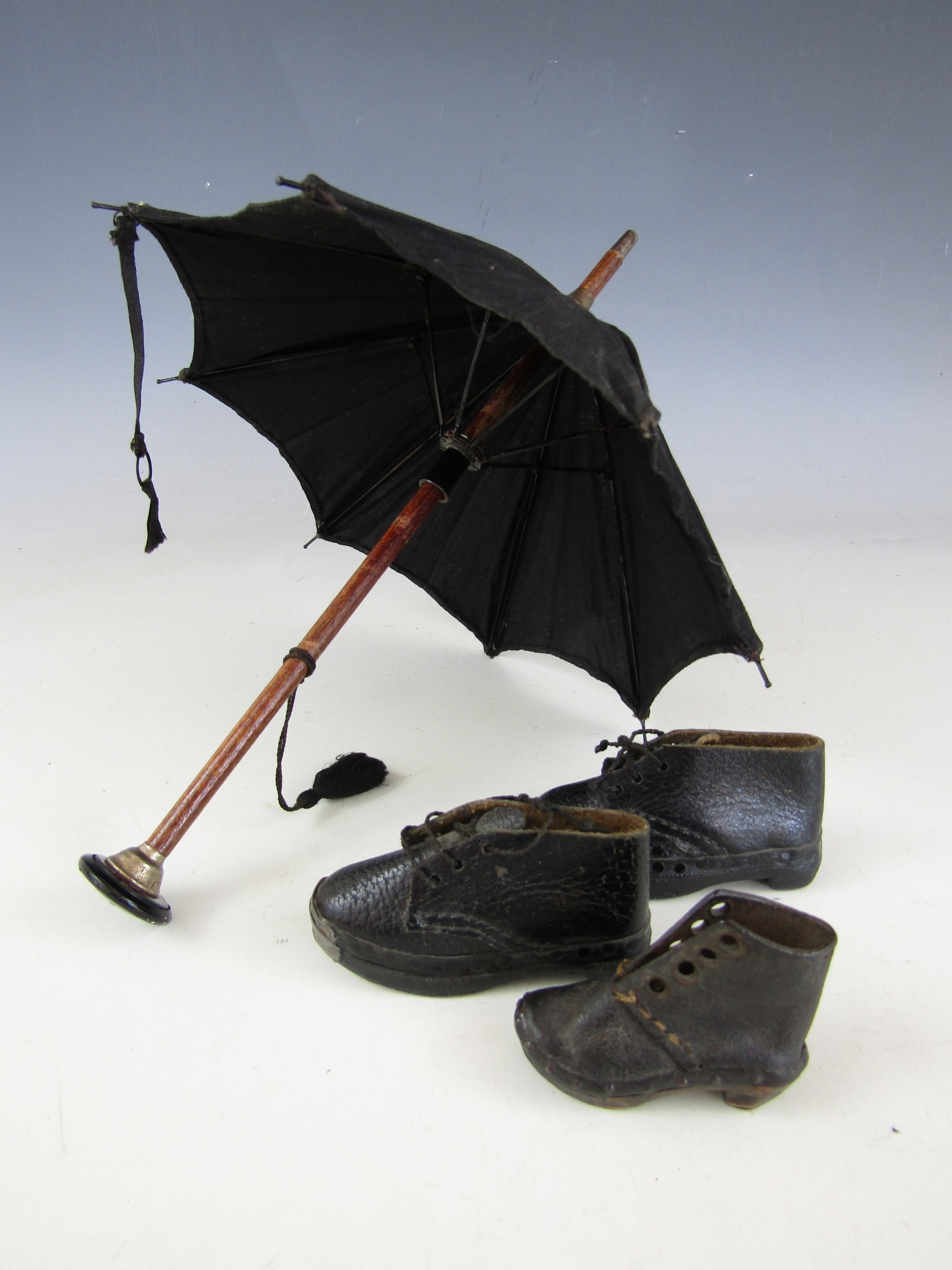 A doll's parasol together with a pair of doll's shoes and one other