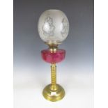 A cranberry glass and brass oil lamp