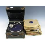 A vintage portable gramophone with a quantity of records