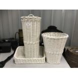 A contemporary white rattan set of storage baskets