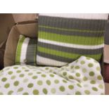 A pair of contemporary woven throws in cream with green polka dots, together with three down