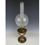 A brass oil lamp with etched glass shade