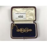 A cased Victorian 9ct gold bar brooch, surmounted by rope twist annuli, foliage and a flower head,