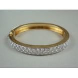 A diamond and high carat yellow metal hinged bangle, the face set with precious white metal, saltire