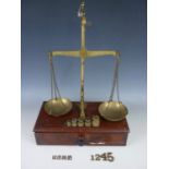 A set of Victorian counter top brass beam scales by Calipe, Dettmer and Co, on a mahogany base