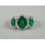 A contemporary emerald, diamond and 18ct white gold dress ring, having three graded oval cut