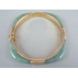 A high carat yellow metal and jade bangle, of rounded square section, mounted to each face with an