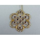 An Edwardian lady's garnet and seed pearl pendant necklace, in the form of a flower head, with