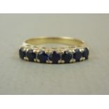 A sapphire set half hoop eternity ring, having seven round-cut stones each of approximately .10ct,