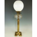 A 19th Century lacquered brass columnar oil lamp, with clear glass reservoir and milk glass shade,