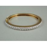 A diamond and yellow metal hinged bangle, the face set with precious white metal, wishbone