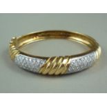 A diamond and high carat yellow metal hinged bangle, the face being spirally fluted surrounding