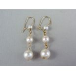 A pair of pearl and yellow metal pendant earrings, each comprising three graded pearls suspended