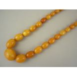 A vintage butterscotch amber necklace of graded ovoid beads, 72 cm, 60.5g, largest bead 26 x 21 mm