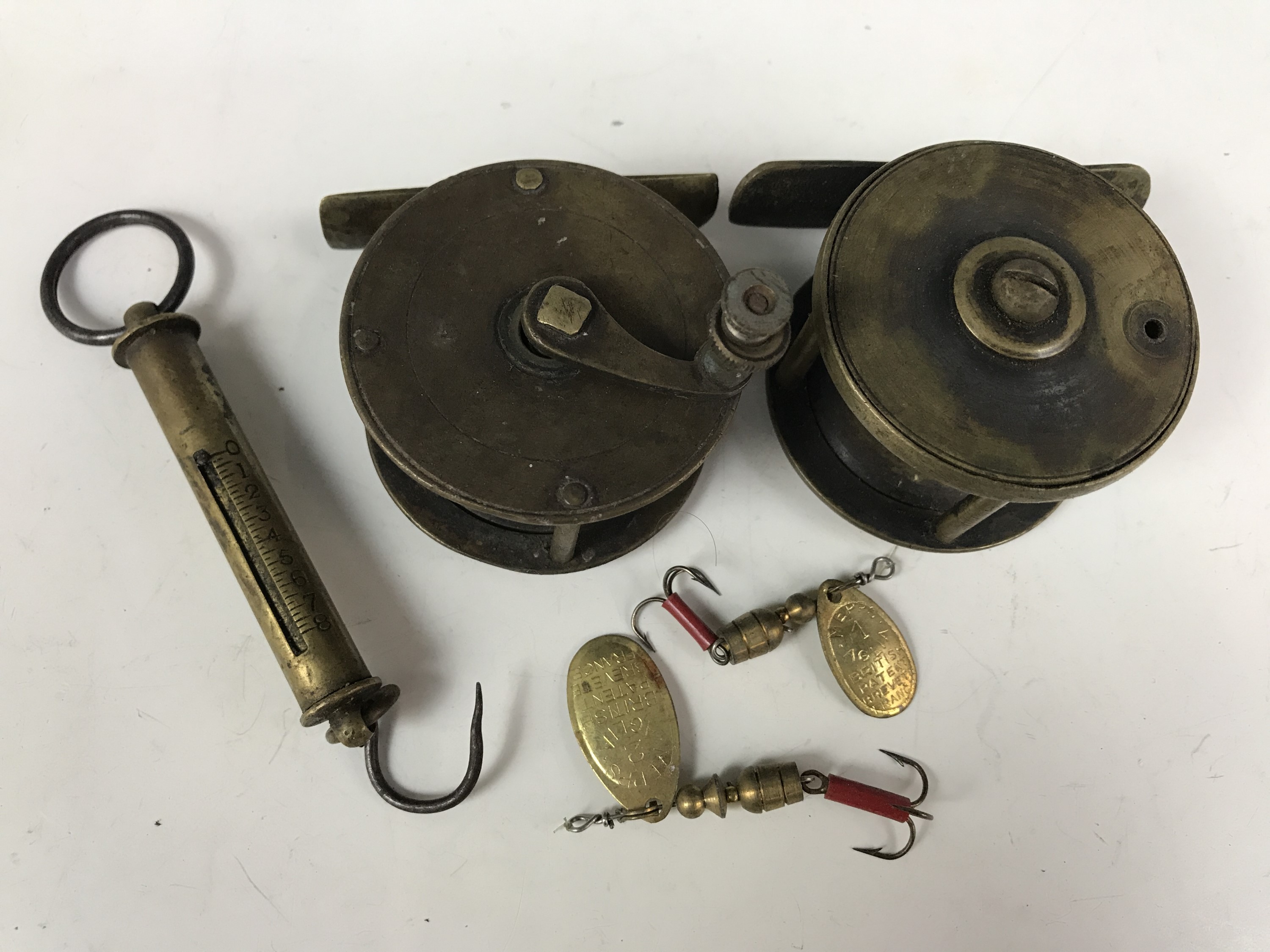 Two vintage small brass fishing reels together with a brass spring balance and two Mepps spinners