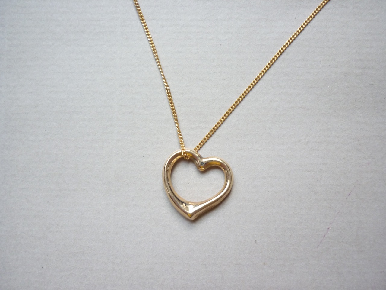 A yellow metal heart shaped pendant on chain, the latter stamped 750, 3.1g total