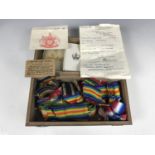 A wooden box containing a quantity of military medal ribbons, medal cartons and related ephemera