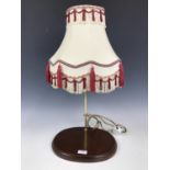 A contemporary table lamp with a cream and red shade
