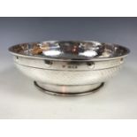 An Edwardian silver Arts and Crafts style fruit bowl, of shallow form raised over a cylindrical