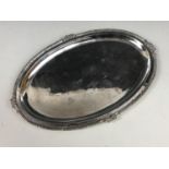 A white metal card tray, of oval shape, having a cabled rim decorated with a floral sprig to each