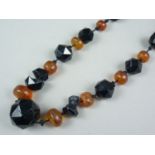 An antique polished amber and faceted jet bead necklace