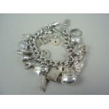 A vintage silver charm bracelet and heart shaped padlock clasp adorned with an assortment of
