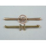 An Edwardian yellow metal bar brooch centrally surmounted by a reticulated swastika, stamped 9ct,