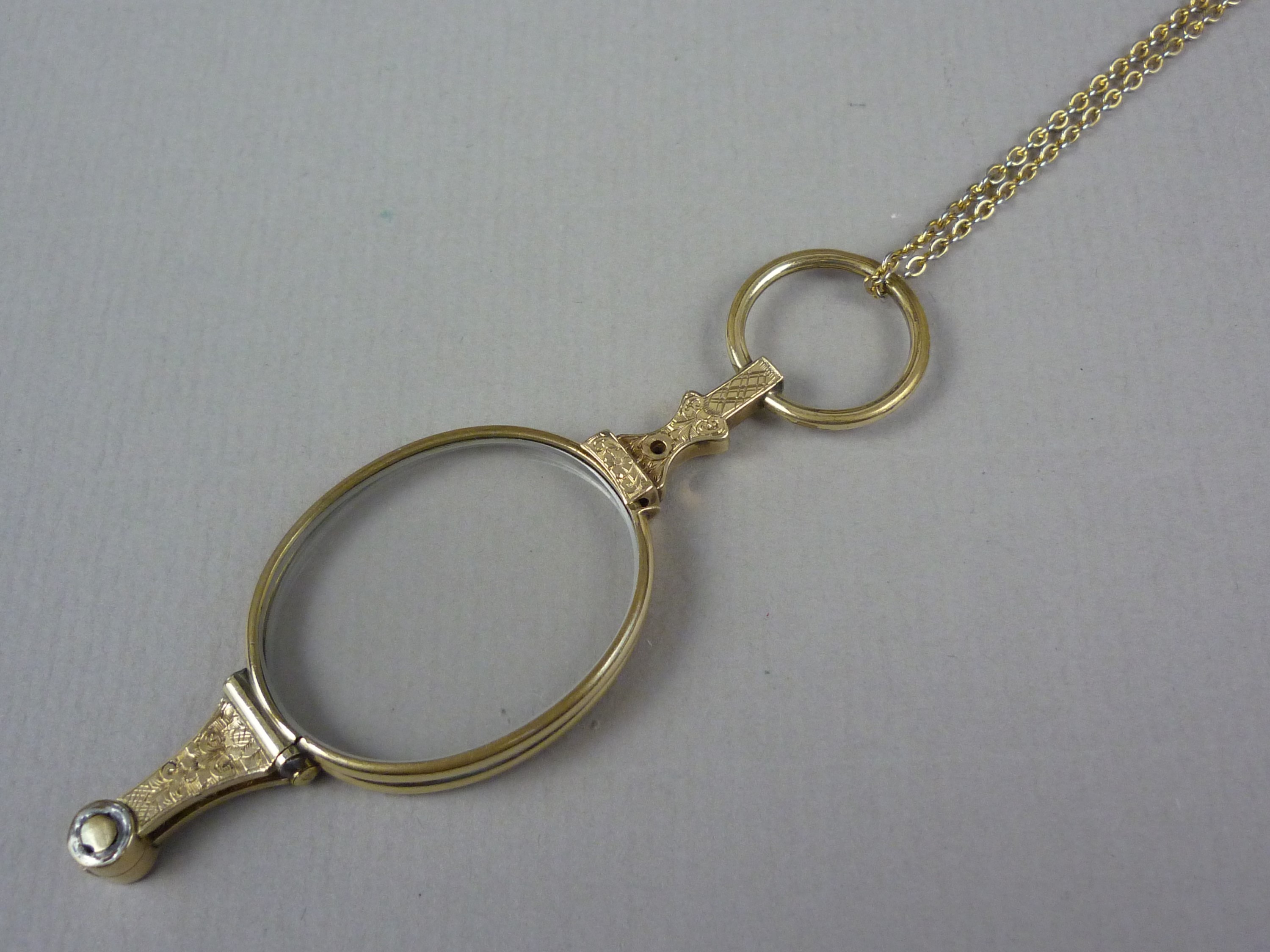 An early 20th Century rolled gold lorgnette, with engraved decoration, on a rolled-gold neck chain