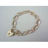 A yellow metal curb link bracelet with heart shaped padlock clasp, stamped '9ct', 12.4g