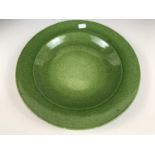 A studio pottery charger by Tobias Harrison, with green speckled glaze, signature inscribed to base,